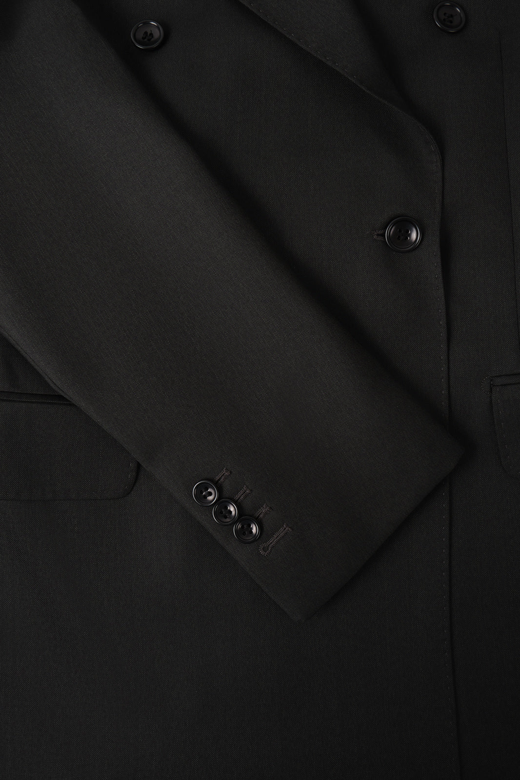 Vue sur fond blanc d'une manche de costume croisé couleur uni noir, sur un tissu en 100% laine de chez Vitale Barberis Canonico