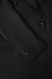 Vue sur fond blanc d'une manche de costume croisé couleur uni noir, sur un tissu en 100% laine de chez Vitale Barberis Canonico