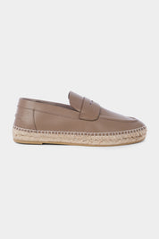 Vue de côté d'une espadrille en cuir beige avec une semelles en corde tressée. Elle a un design de mocassin avec des coutures apparentes sur le dessus.