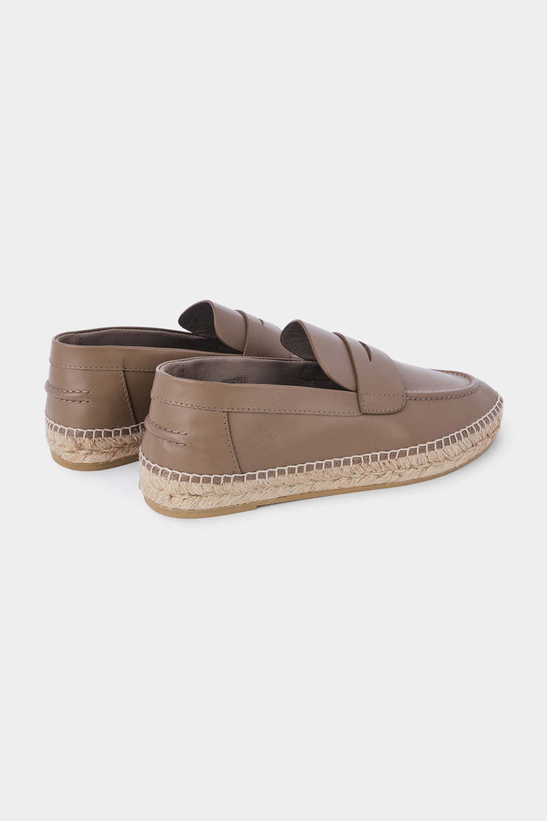 Vue de dos d'une paire d'espadrilles en cuir beige avec des semelles en corde tressée. Les chaussures ont un design de mocassin avec des coutures apparentes sur le dessus. 
