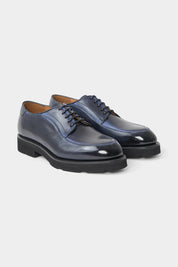 Vue sur fond blanc de souliers à lacets patiné bleu. Sur une patine artisanale made in Italy.