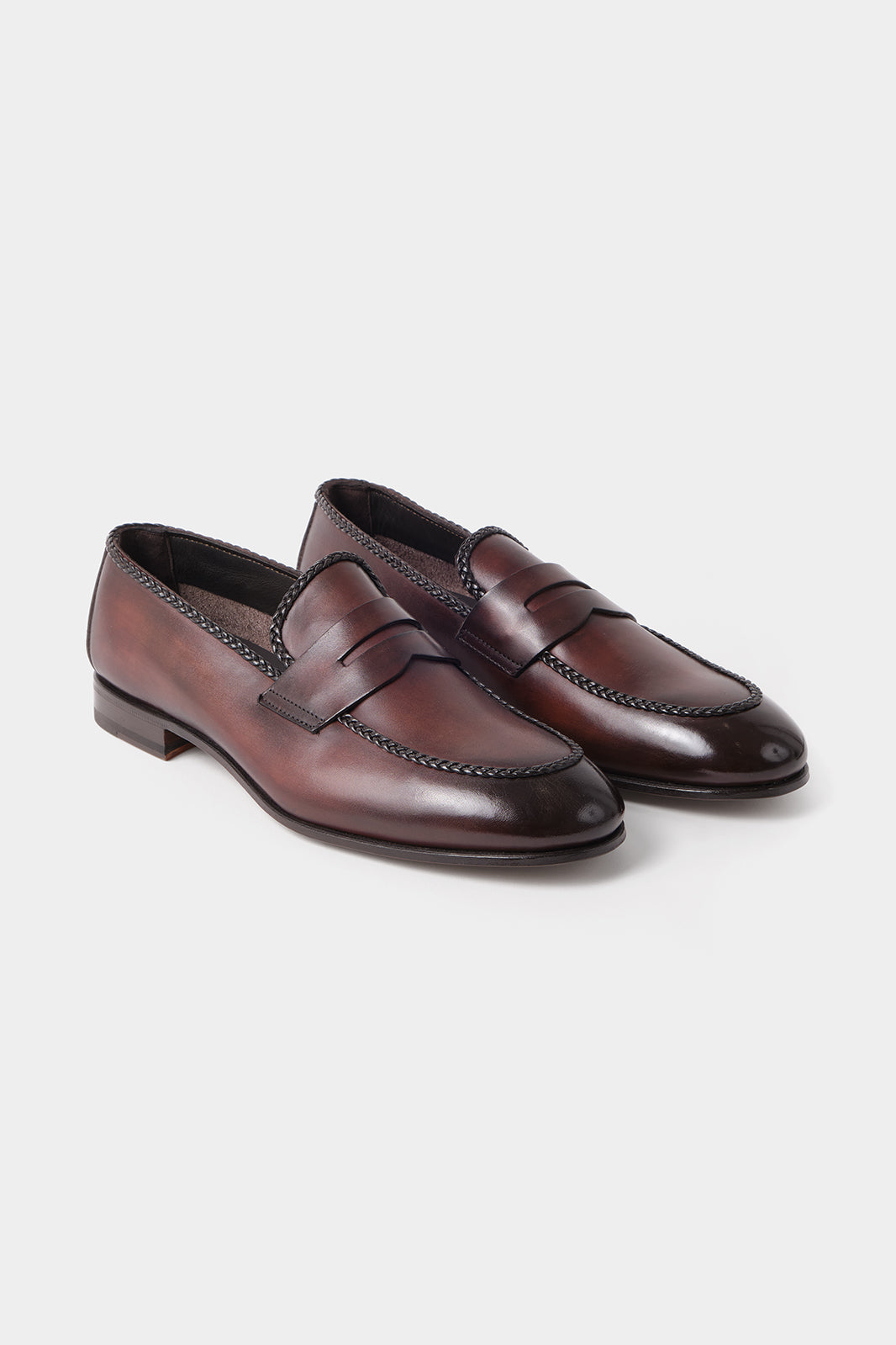 Vue sur fond blanc d'une paire de mocassins en cuir marron avec semelle lisse.