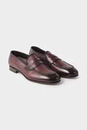 Vue sur fond blanc d'une paire de mocassins en cuir marron avec semelle lisse.