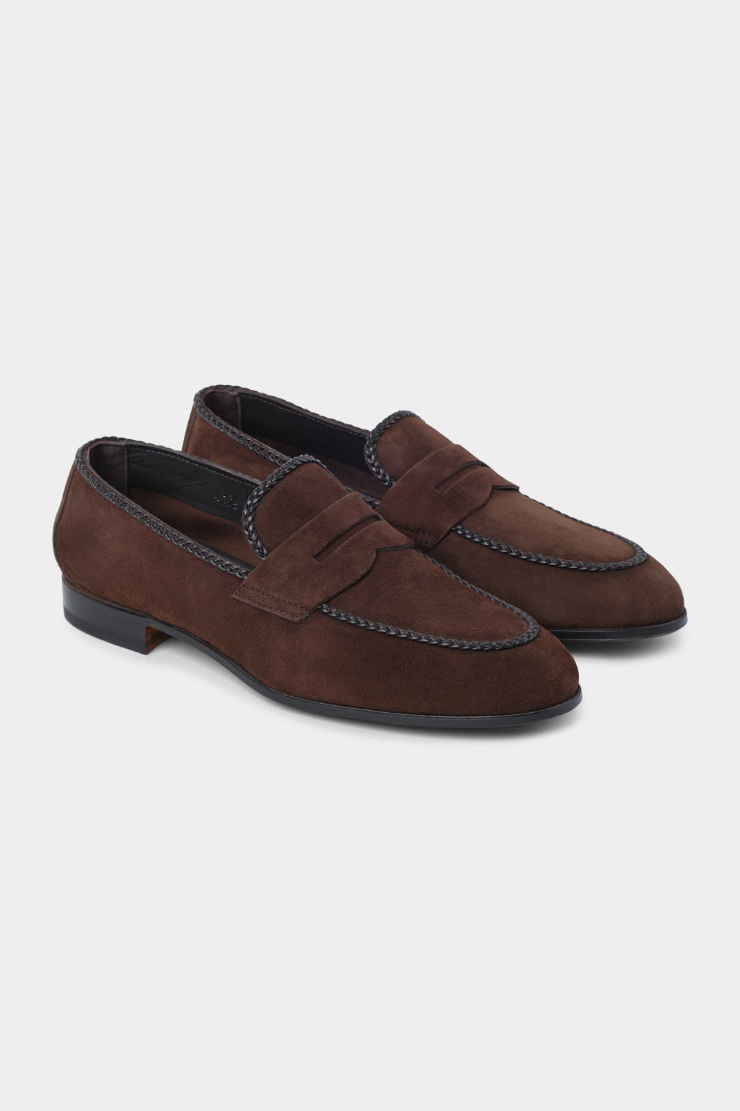 Vue sur fond d'un mocassin type "penny loafer" en peau marron avec les bordures tréssées en cuir