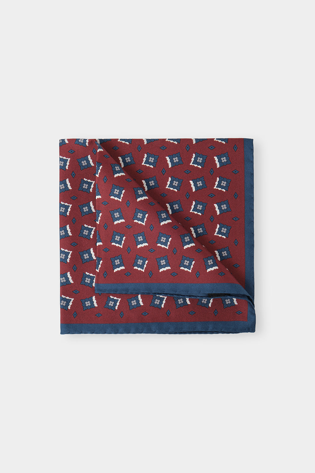 Vue sur fond d'une pochette imprimée bordeaux à fleurs marine en 100% soie fabriqué en Italie.