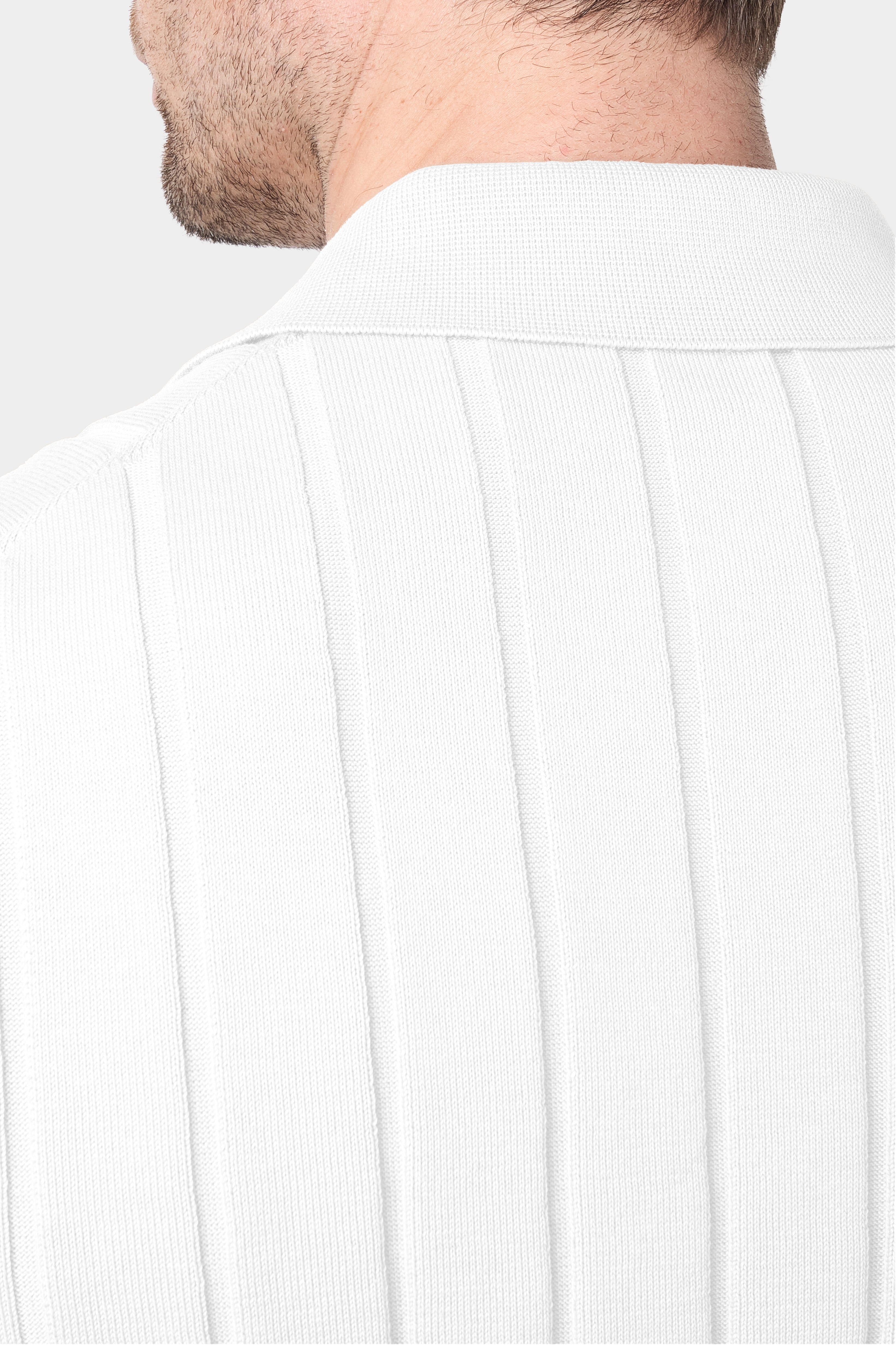 Un gros plan de dos d'une chemise polo blanche avec des rayures verticales, mettant en évidence le col. Le tissu présente une matière en maille fine en coton.