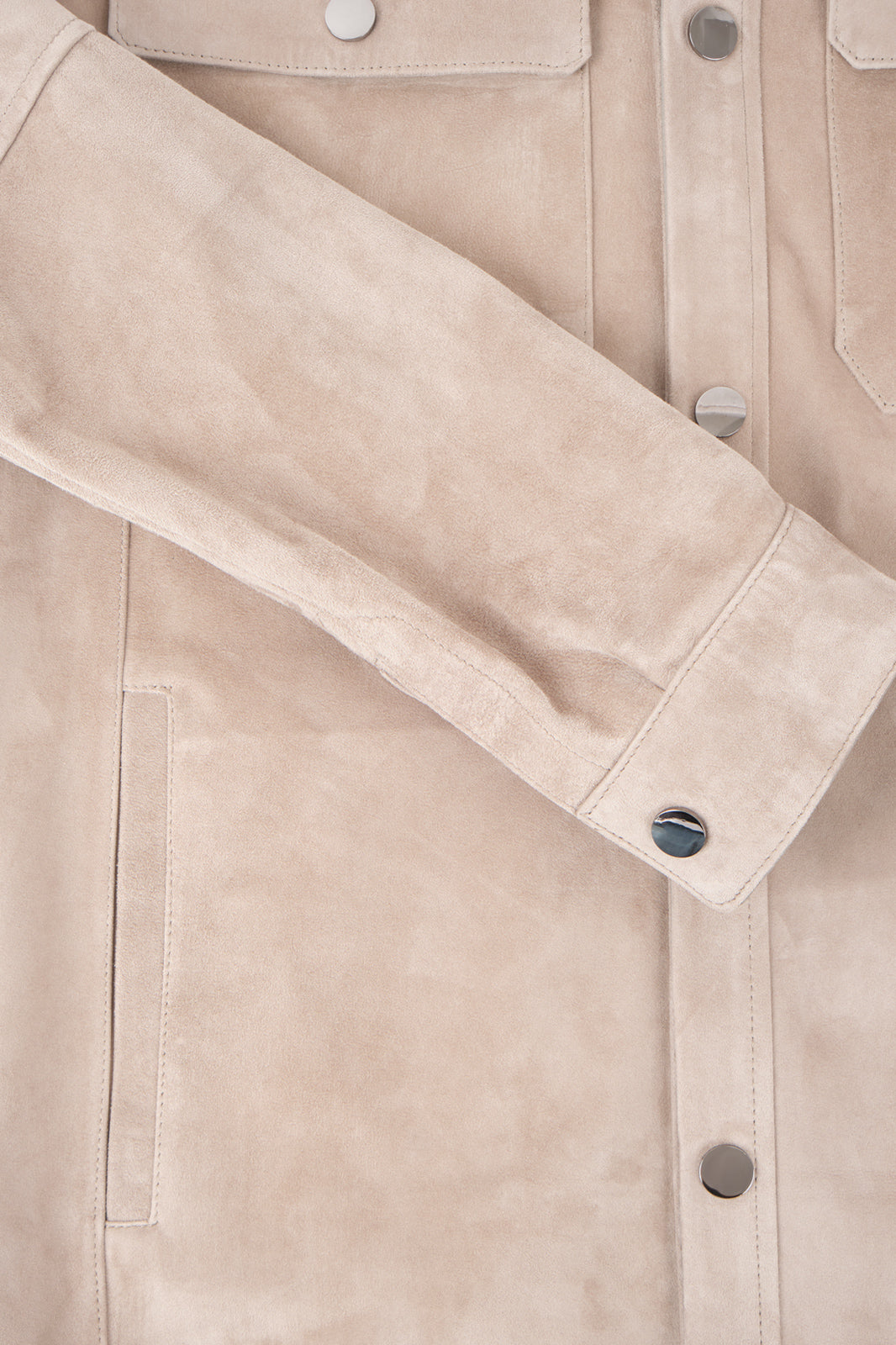 Vue sur fond blanc d'une sur-chemise en peau beige très légère avec boutonnage à pression lisse argenté, poche poitrine à rabat et poches latérales.