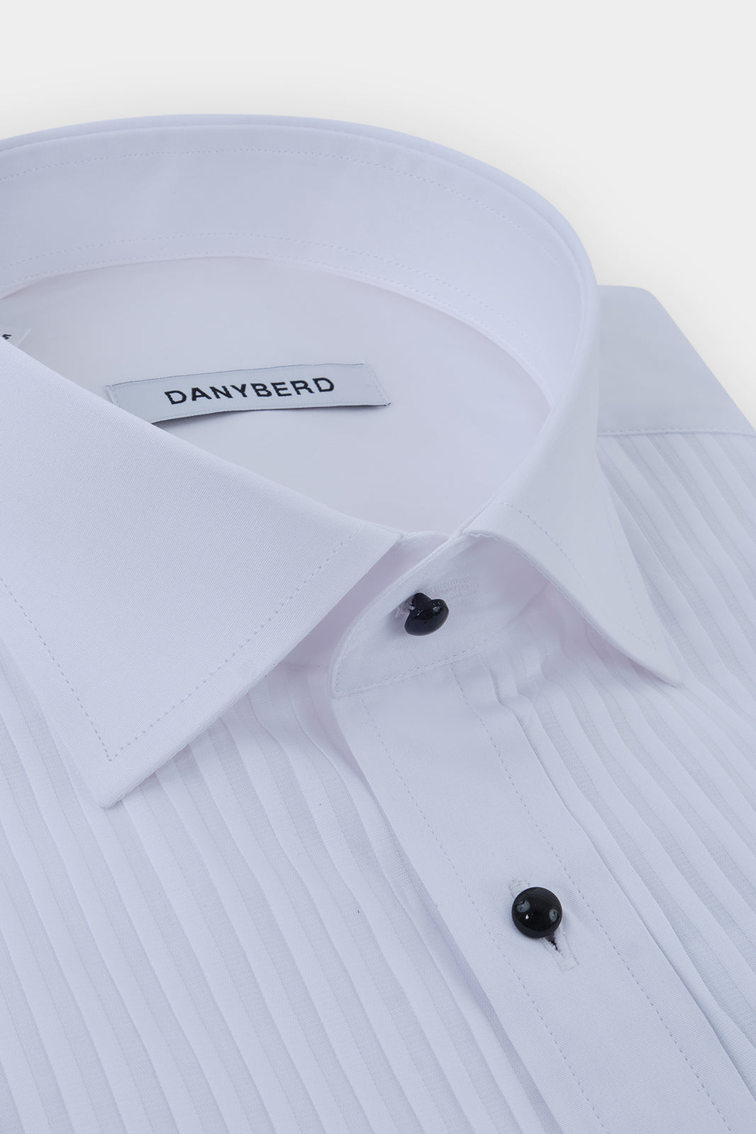 Vue sur fond blanc d'une chemise en 100% coton de smoking blanche à plastron avec boutonnage boule noir.