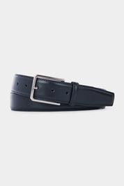 Ceinture en cuir noir avec une boucle rectangulaire en métal argenté, posée à plat sur un fond gris clair