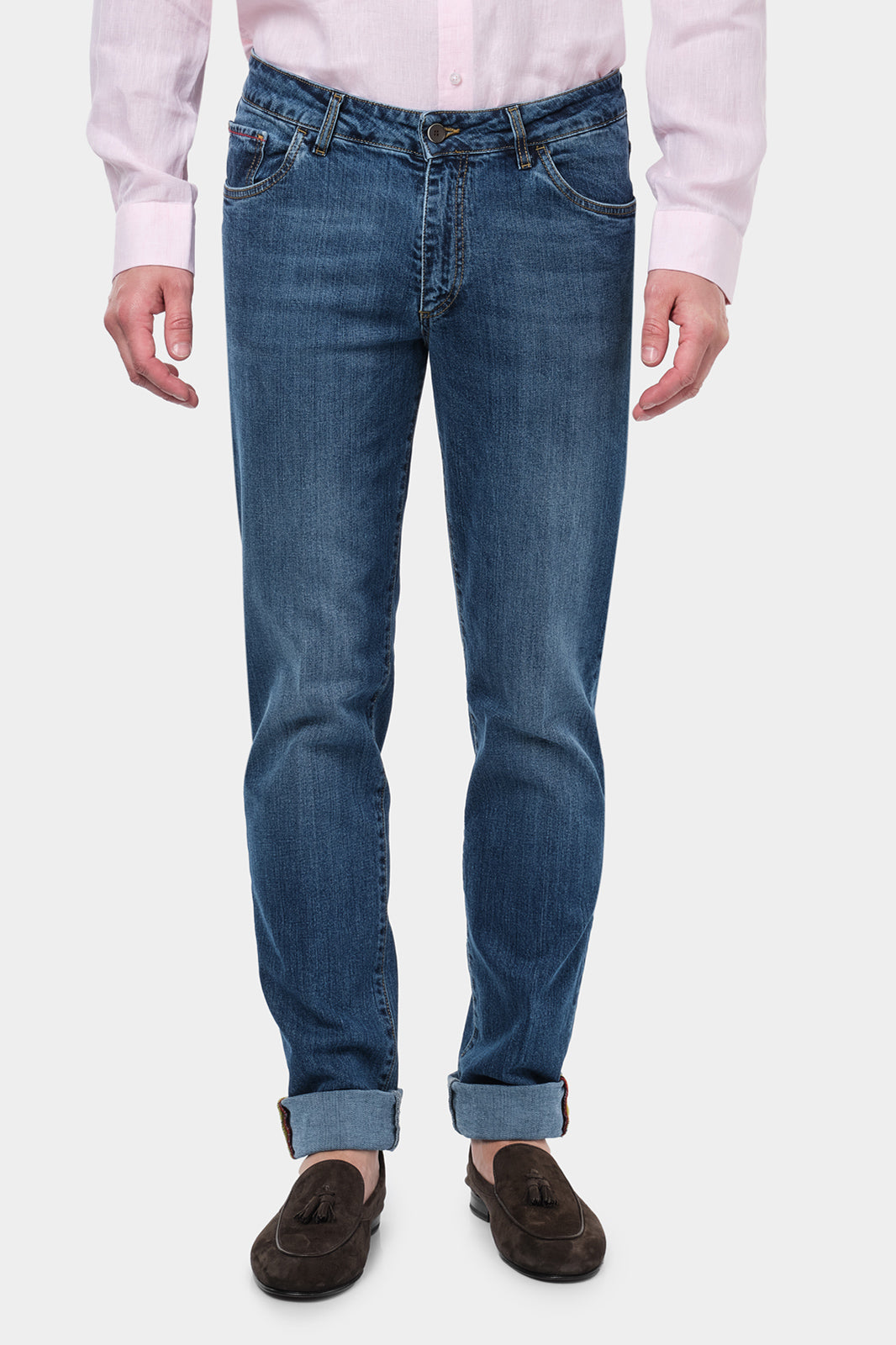  Homme portant un jean en coton et élasthanne de couleur usé. Il porte également des mocassins en daim marron.  