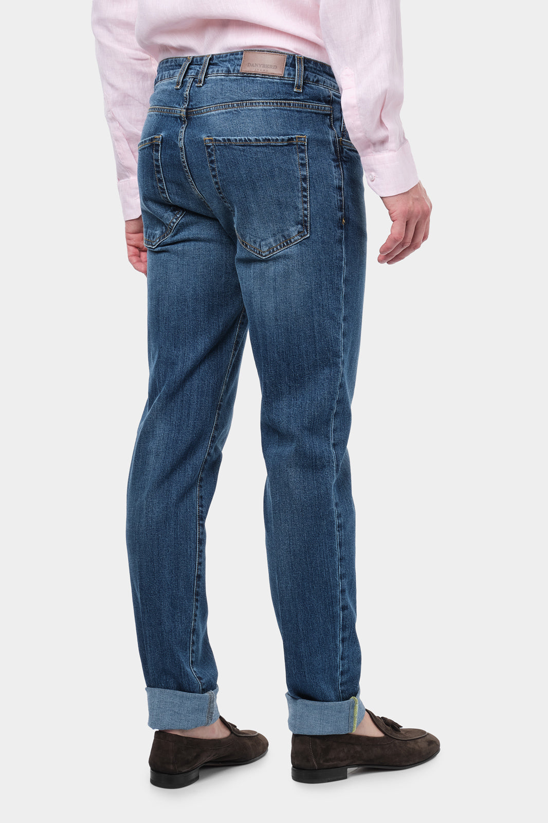  Homme de dos portant un jean en coton et élasthanne de couleur usé. Il porte également des mocassins en daim marron.  Il porte également une chemise en lin rose.